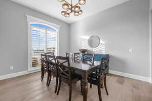 Dining room with light wood-type flooring and a chandelier