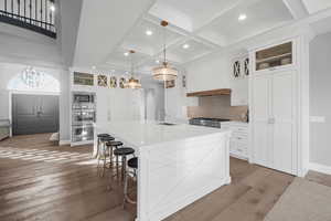 Kitchen with dark hardwood / wood-style flooring, stainless steel appliances, pendant lighting, white cabinetry, and an island with sink