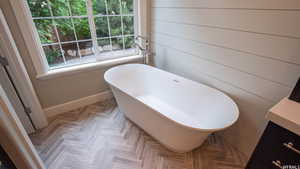 Bathroom featuring vanity, a tub to relax in, parquet floors, and wooden walls