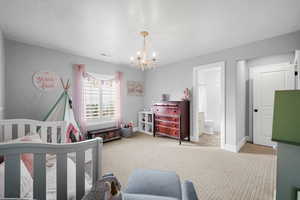 Bedroom featuring light carpet, connected bathroom, and an inviting chandelier