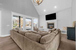 Living room featuring light wood-type flooring, high vaulted ceiling, and an inviting chandelier