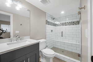 Bathroom featuring vanity, toilet, and a shower with shower door