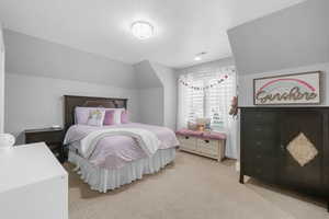 Bedroom with light carpet and vaulted ceiling