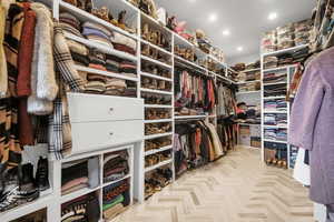 Walk in closet with light parquet flooring