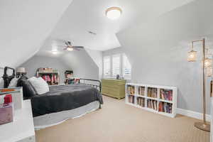 Carpeted bedroom featuring vaulted ceiling and ceiling fan