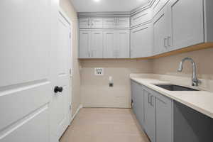 Washroom featuring cabinets, hookup for a washing machine, electric dryer hookup, sink, and light tile patterned floors