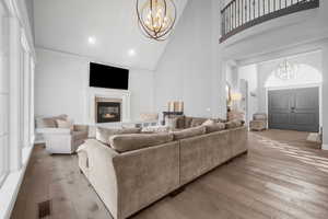 Living room with light wood-type flooring, high vaulted ceiling, and an inviting chandelier