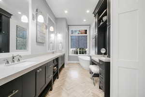 Bathroom featuring vanity, parquet floors, and a bath