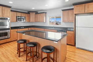 Kitchen featuring a kitchen bar, sink, stainless steel appliances, and light wood-type flooring