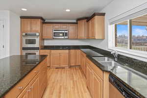 Kitchen with granite countertops, stainless steel appliances, light hardwood / wood-style floors, and a kitchen island