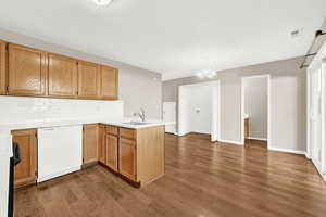 Kitchen with dishwasher, sink, dark hardwood / wood-style floors, kitchen peninsula, and a chandelier