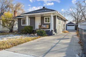 Bungalow-style house with a porch, a garage, and an outbuilding