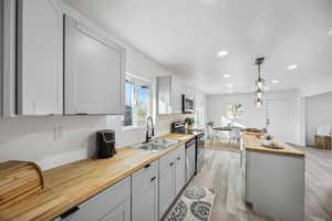 Kitchen with wooden counters, appliances with stainless steel finishes, a wealth of natural light, sink, and pendant lighting