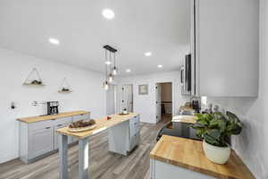 Kitchen with butcher block counters, sink, gray cabinets, and hanging light fixtures