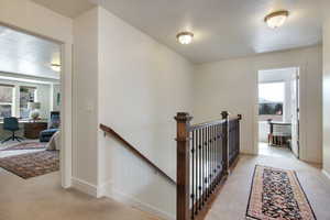 Hall with plenty of natural light and light colored carpet