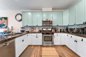 Kitchen featuring decorative backsplash, sink, light wood-type flooring, and appliances with stainless steel finishes