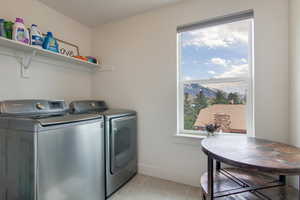 Laundry area with washer and dryer and light tile patterned floors