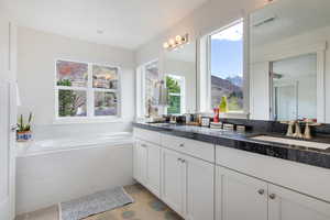 Bathroom with tile patterned flooring, a mountain view, vanity, and a relaxing tiled tub