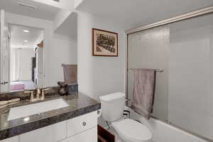 Full bathroom featuring vanity, enclosed tub / shower combo, and toilet