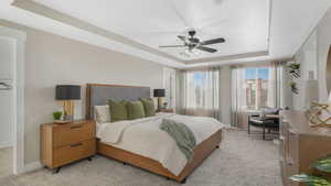 Carpeted bedroom featuring a tray ceiling and ceiling fan