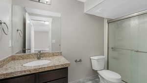 Bathroom with vanity, toilet, and a shower with shower door