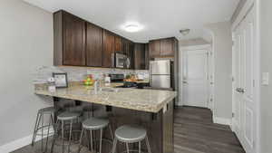 Kitchen with a kitchen bar, kitchen peninsula, sink, and appliances with stainless steel finishes