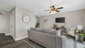 Living room with ceiling fan and dark hardwood / wood-style flooring