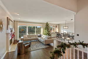 Living room featuring a premium fireplace, crown molding, dark wood-type flooring, and a notable chandelier