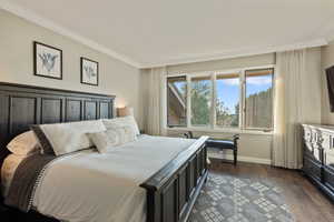 Bedroom featuring crown molding and dark wood-type flooring