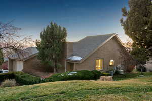 Property exterior at dusk featuring central AC unit, a garage, and a yard