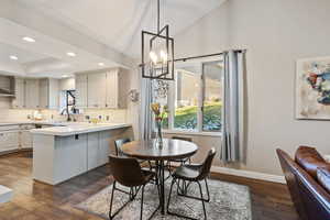 Kitchen with backsplash, dark hardwood / wood-style floors, decorative light fixtures, kitchen peninsula, and a breakfast bar area