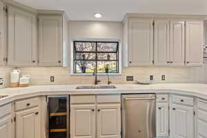 Kitchen with wine cooler, white cabinetry, sink, and decorative backsplash