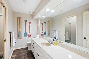 Bathroom with a shower with door, vanity, wood-type flooring, and toilet