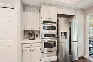 Kitchen featuring backsplash, stainless steel appliances, white cabinetry, and dark hardwood / wood-style floors