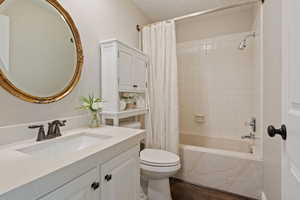 Full bathroom with shower / tub combo with curtain, vanity, wood-type flooring, and toilet