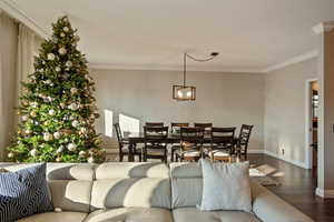 Living room featuring hardwood / wood-style floors, ornamental molding, and an inviting chandelier