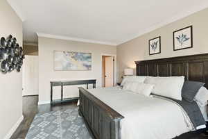 Bedroom featuring crown molding and dark wood-type flooring