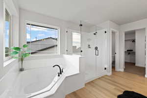 Bathroom featuring wood-type flooring and shower with separate bathtub