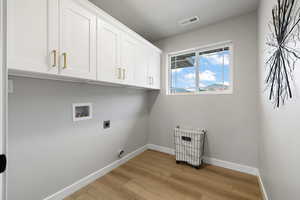 Laundry room with hookup for an electric dryer, cabinets, hookup for a washing machine, and light hardwood / wood-style flooring