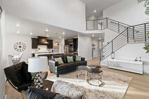 Living room with light hardwood / wood-style floors and a high ceiling