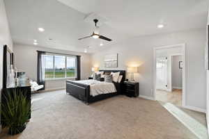 Bedroom with light colored carpet, ceiling fan, and lofted ceiling