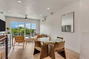 Dining room featuring ceiling fan, a textured ceiling, a wall mounted AC, and light hardwood / wood-style flooring