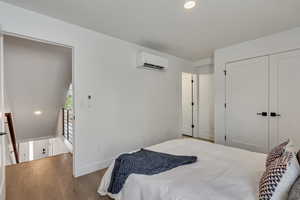 Bedroom with a closet, light hardwood / wood-style floors, and a wall mounted AC