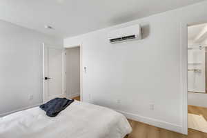 Bedroom featuring light hardwood / wood-style flooring and a wall unit AC