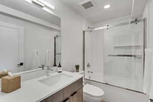 Full bathroom with combined bath / shower with glass door, vanity, and toilet