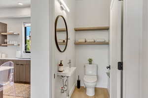 Bathroom with toilet, wood-type flooring, and sink