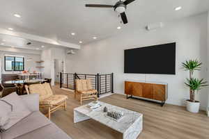 Living room featuring a wall mounted AC, ceiling fan, and light hardwood / wood-style floors