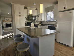 Kitchen with white cabinets, wood-type flooring, white refrigerator, and sink