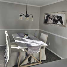 Dining space with carpet floors, a chandelier, and ornamental molding