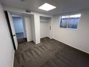 Unfurnished bedroom featuring dark carpet and a closet